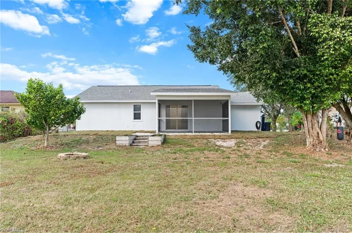 Back of property featuring a lawn, a sunroom, and roof with shingles