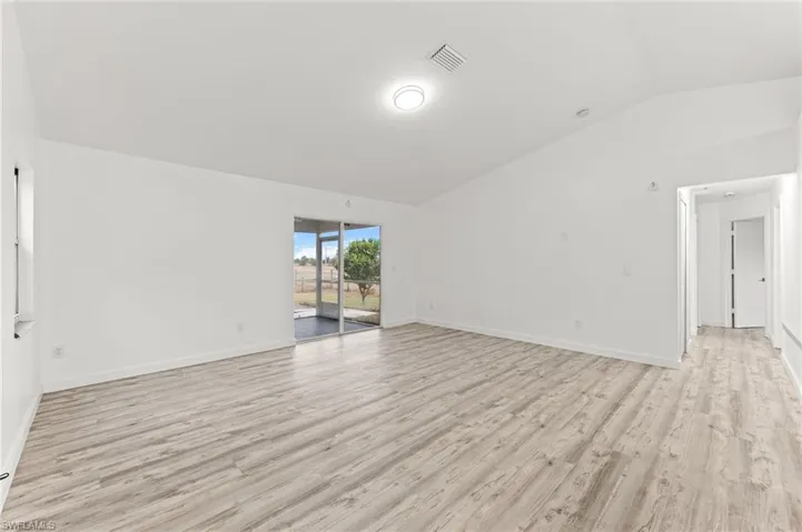 Spare room with vaulted ceiling and light wood-type flooring