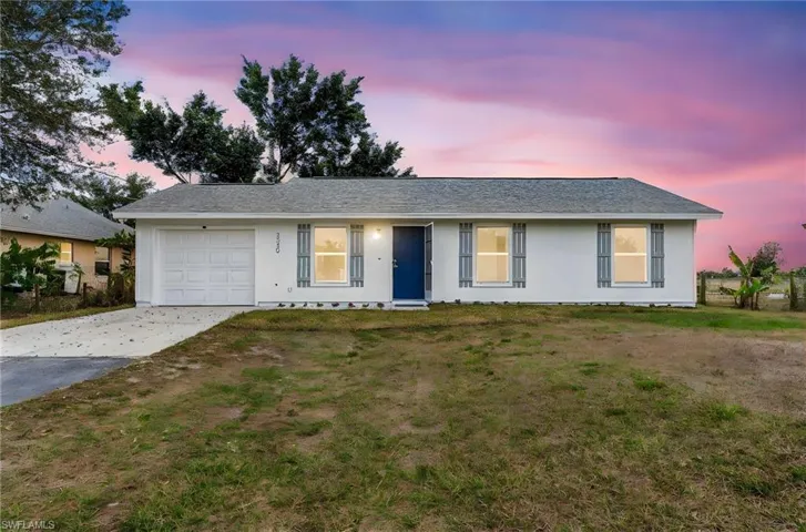 Single story home with concrete driveway, an attached garage, stucco siding, and a front lawn