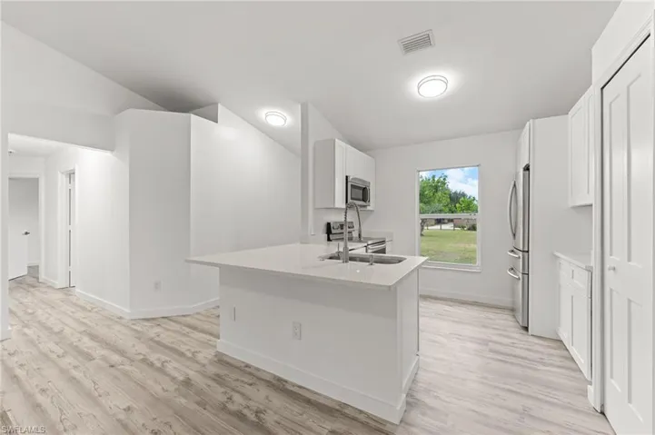 Kitchen featuring white cabinets, stainless steel appliances, a peninsula, and light wood-type flooring