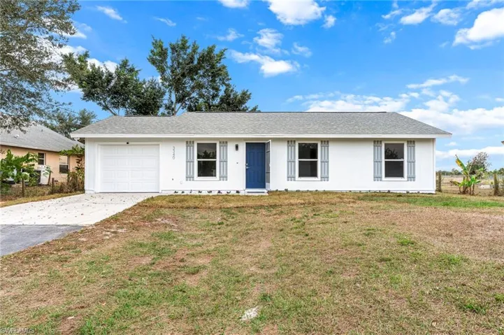 Single story home featuring driveway, an attached garage, a shingled roof, and a front yard