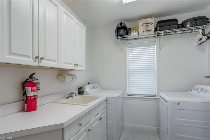 Laundry room featuring washer and clothes dryer, cabinet space, baseboards, and light tile patterned floors