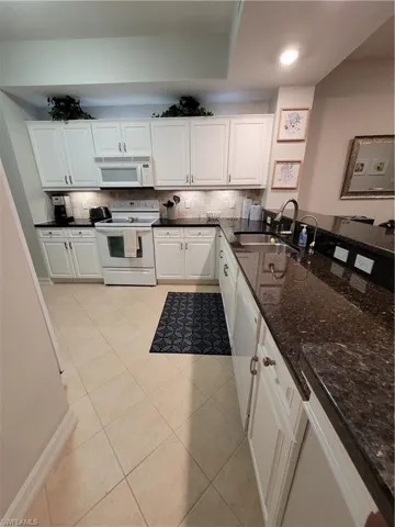 Kitchen with sink, white cabinets, backsplash, and range