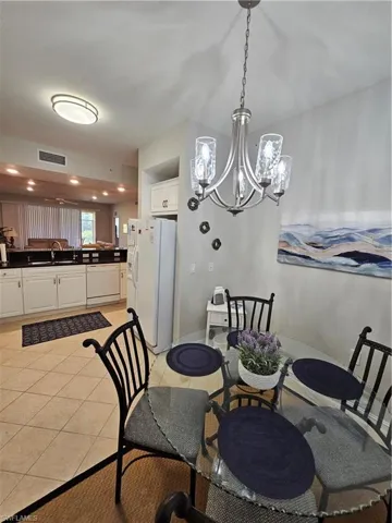 Dining room with a chandelier, light tile patterned floors, and recessed lighting