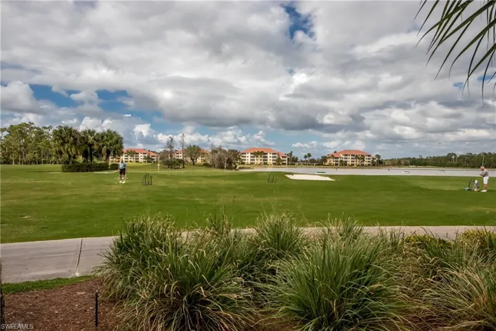 View of community with view of golf course, a water view, and a lawn