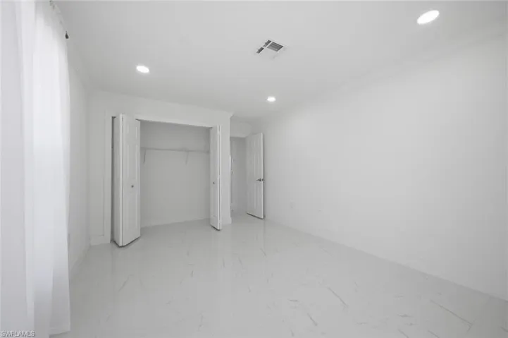Interior space featuring large-format tile flooring with veining, recessed lighting, and built-in closet storage