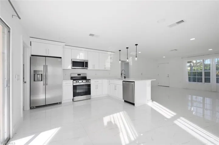 Kitchen featuring white cabinetry, stainless steel appliances, a peninsula with stone-finish countertops, recessed lighting, and tile flooring