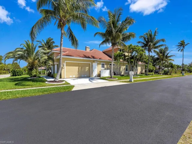 View of front of home featuring stucco siding, an attached garage, driveway, a tiled roof, and a front yard