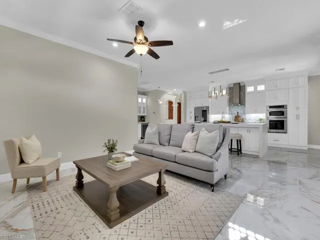 Living room featuring light marble finish flooring, ceiling fan, recessed lighting, baseboards, and arched walkways