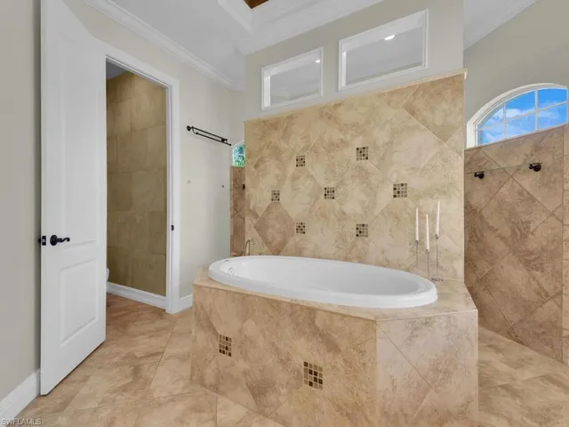 Bathroom featuring ornamental molding, a bath, and a tile shower