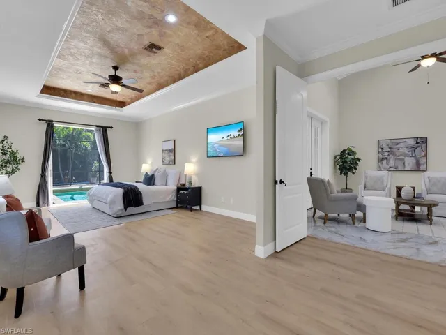 Bedroom featuring a tray ceiling, access to outside, light wood finished floors, crown molding, and baseboards