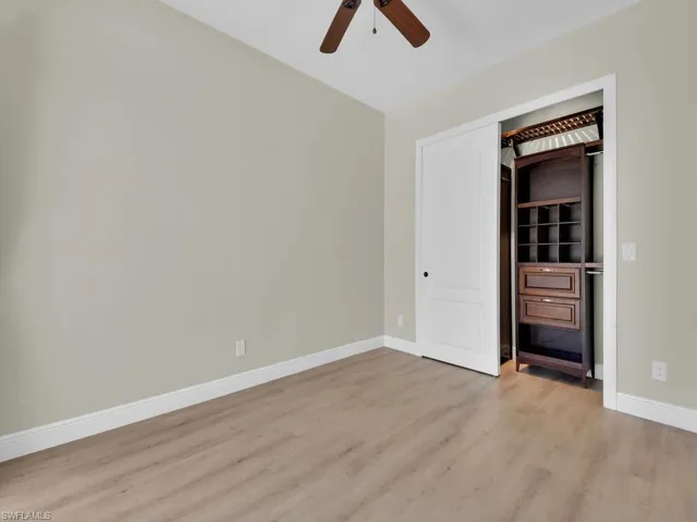 Empty room with light wood-style flooring, a ceiling fan, and baseboards