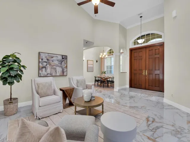 Foyer entrance with a chandelier, marble tiled flooring, baseboards, crown molding, and ceiling fan