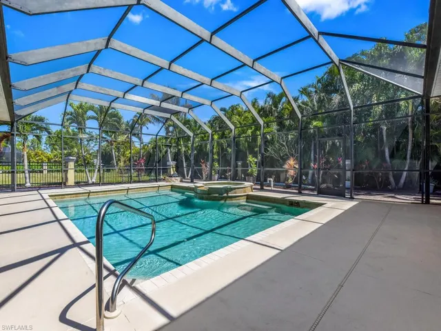 View of swimming pool featuring a patio, a pool with connected hot tub, and glass enclosure