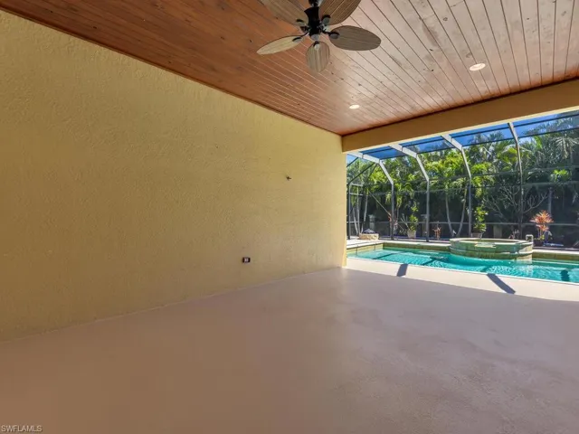 View of pool with a patio area, a ceiling fan, a pool with connected hot tub, and glass enclosure