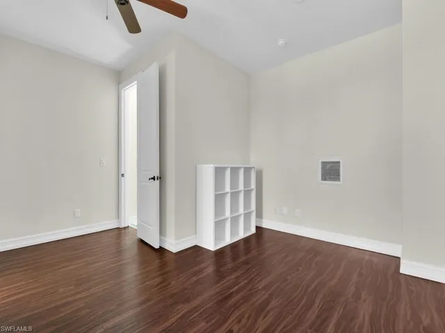 Unfurnished room featuring ceiling fan, baseboards, and dark wood-style flooring