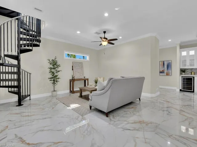 Living area with wine cooler, light marble finish flooring, stairway, recessed lighting, and plenty of natural light