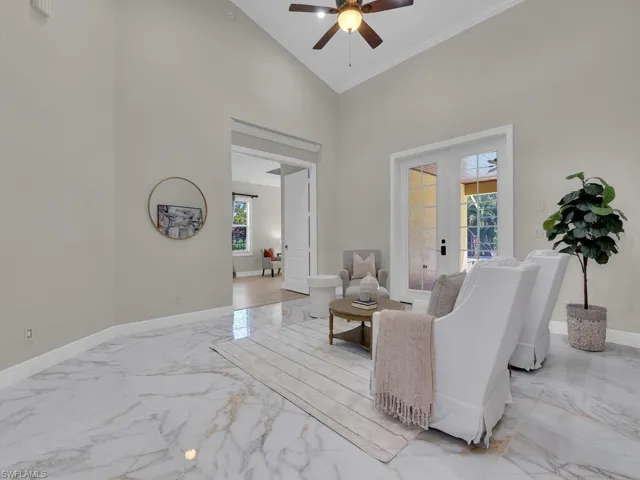 Living room with light marble finish flooring, ceiling fan, baseboards, french doors, and high vaulted ceiling