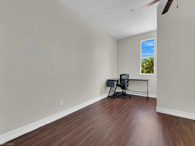 Unfurnished office featuring wood finished floors, baseboards, and a ceiling fan