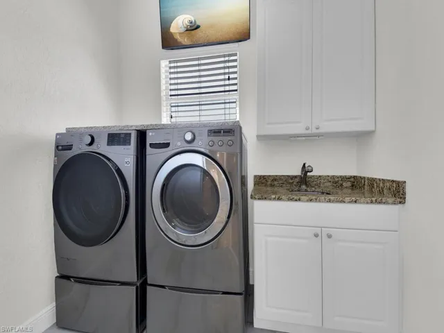 Laundry room featuring washer and dryer, cabinet space, and baseboards