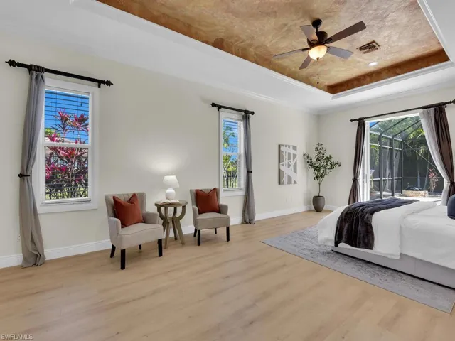 Bedroom with a raised ceiling, light wood-type flooring, access to exterior, and baseboards