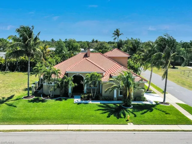 Mediterranean / spanish house with a tiled roof, a front yard, stucco siding, and a chimney