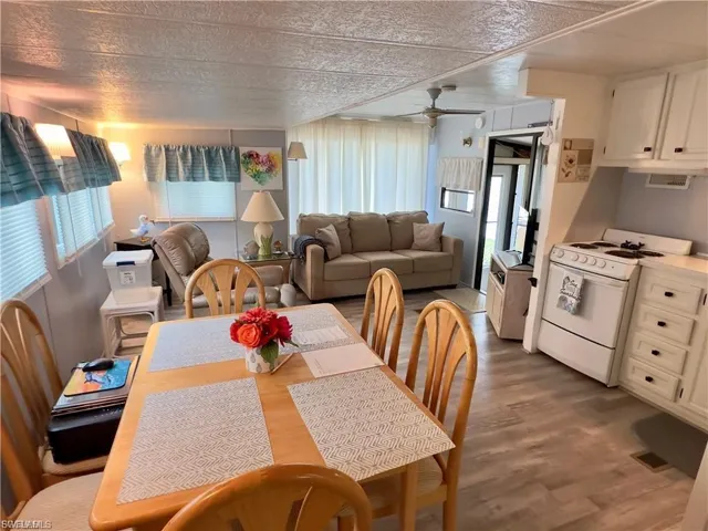 Dining space with healthy amount of natural light, a ceiling fan, wood finished floors, and a textured ceiling