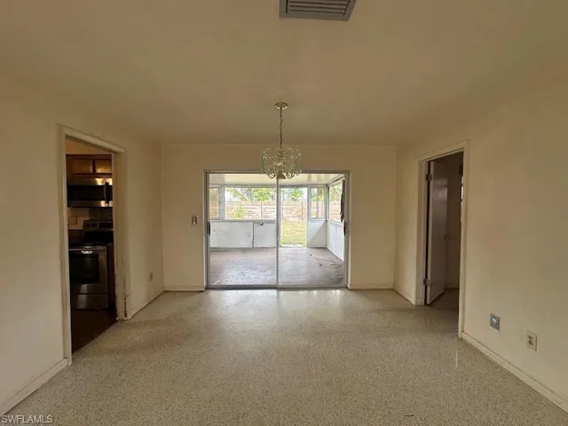 Unfurnished dining area featuring a chandelier and speckled floor