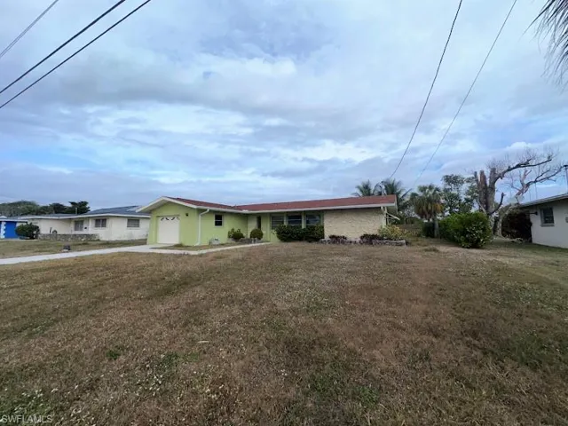 Ranch-style house with a front lawn, an attached garage, and driveway