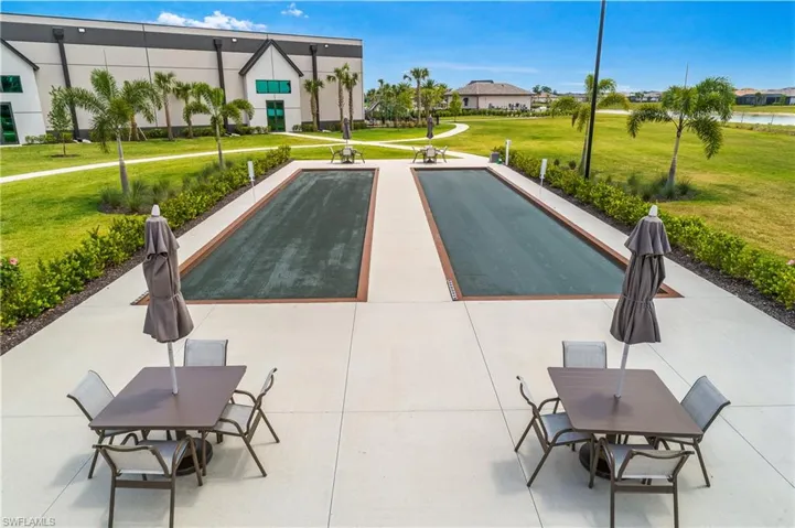 View of property's community featuring a bocce ball area, outdoor dining space, and a patio