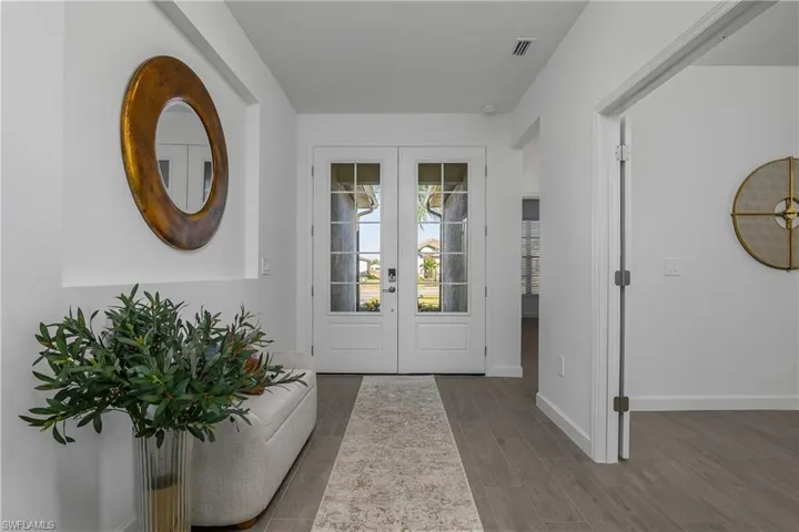 Foyer entrance with french doors and wood finished floors (photo is from staged home in community)