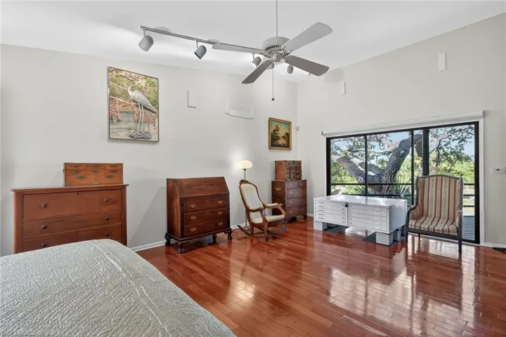 Bedroom featuring track lighting, hardwood / wood-style floors, access to outside, a ceiling fan, and a high ceiling