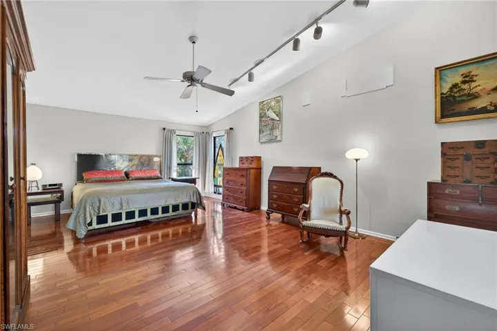 Bedroom featuring track lighting, lofted ceiling, light wood finished floors, and a ceiling fan