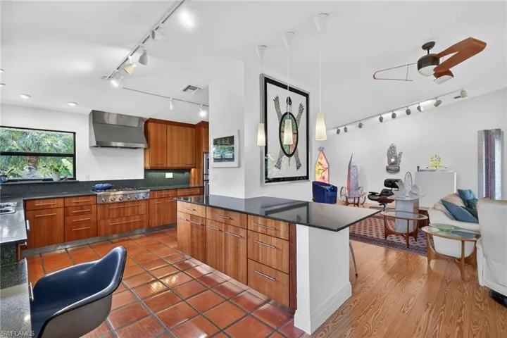 Kitchen featuring dark stone countertops, track lighting, wood finish cabinets, modern cabinets, and ceiling fan