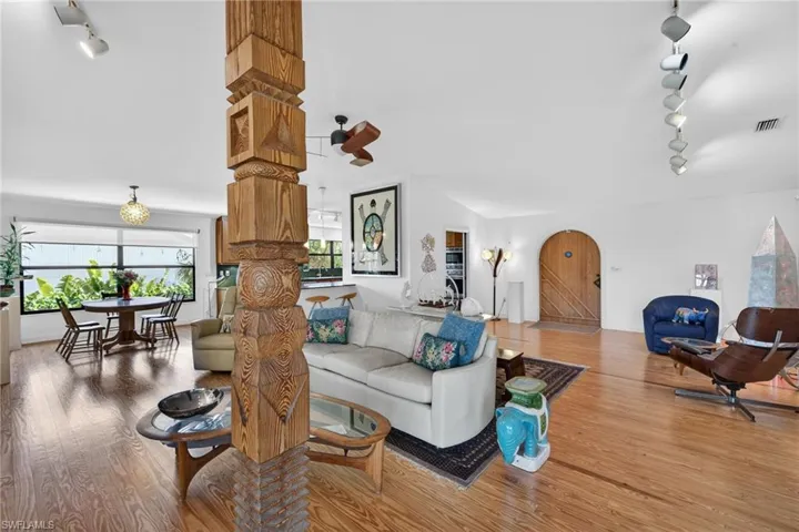 Living area featuring track lighting, ceiling fan, wood finished floors, and arched walkways