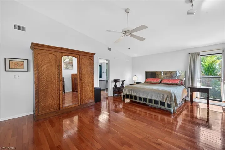 Bedroom featuring hardwood / wood-style floors, vaulted ceiling, ceiling fan, and rail lighting