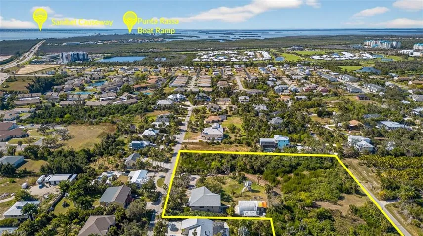 Aerial perspective of suburban area with property parcel outlined and a large body of water