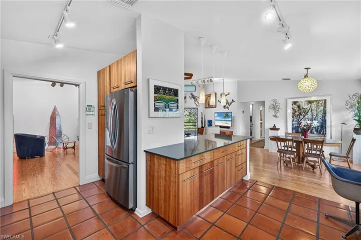 Kitchen with rail lighting, dark stone counters, freestanding refrigerator, wood finish cabinetry, and dark tile patterned flooring