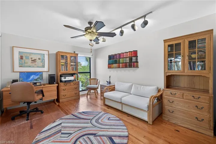 Home office with rail lighting, a ceiling fan, and light wood-style flooring