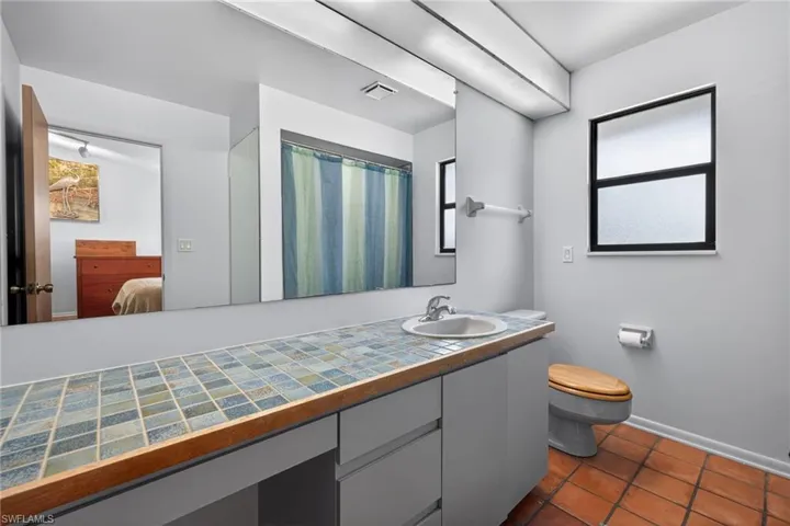 Ensuite bathroom with a shower with shower curtain, vanity, and dark tile patterned floors