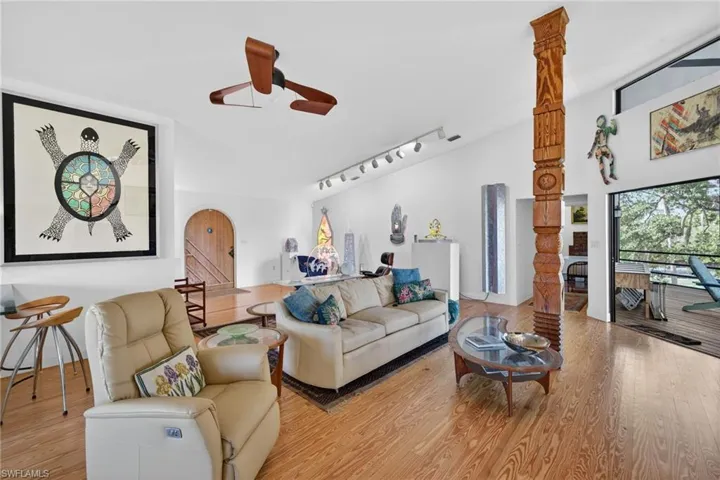 Living room featuring track lighting, a ceiling fan, wood finished floors, and vaulted ceiling