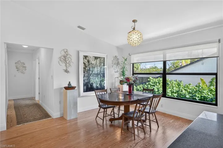 Dining area with vaulted ceiling and light wood-type flooring