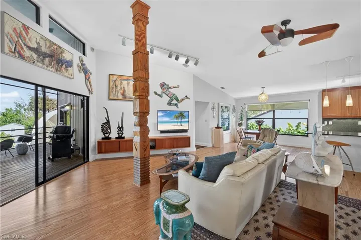 Living area featuring track lighting, ceiling fan, light wood finished floors, and vaulted ceiling