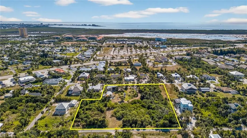 Aerial view of residential area with property parcel outlined and a nearby body of water