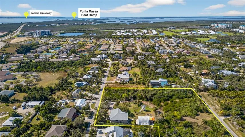 Aerial view of residential area with a nearby body of water and property boundaries highlighted