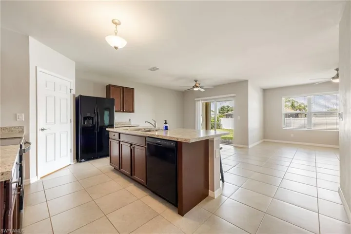 Kitchen with open floor plan, a sink, black appliances, and a ceiling fan