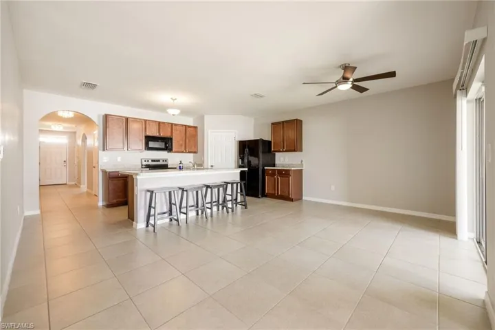 Kitchen featuring arched walkways, a ceiling fan, visible vents, black appliances, and light countertops