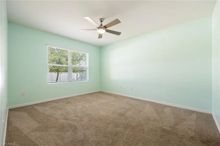 Empty room with carpet floors, baseboards, and a ceiling fan
