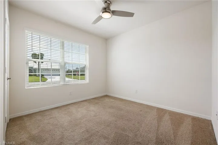 Unfurnished room with ceiling fan, light carpet, and baseboards