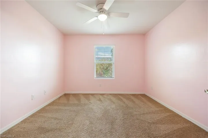 Empty room with baseboards, light colored carpet, and a ceiling fan